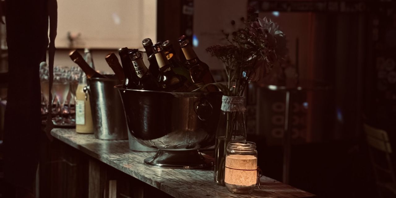 Bartheke mit Flaschen, Blumen und Kerzenlicht, Discokugel im Hintergrund