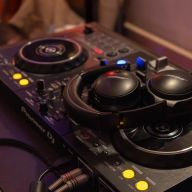 Nahaufnahme eines Pioneer DJ-Controllers mit schwarzen Bose-Kopfhörern.